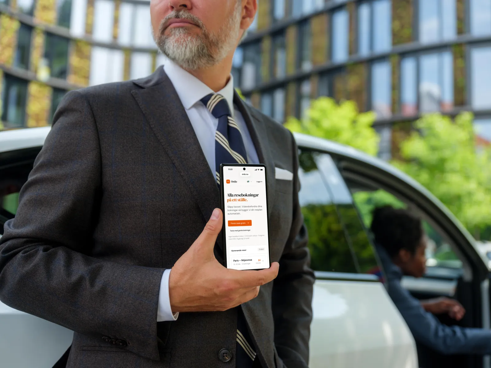 Affärsresenär visar Ordo reseapp med restider på sin mobil vid bil